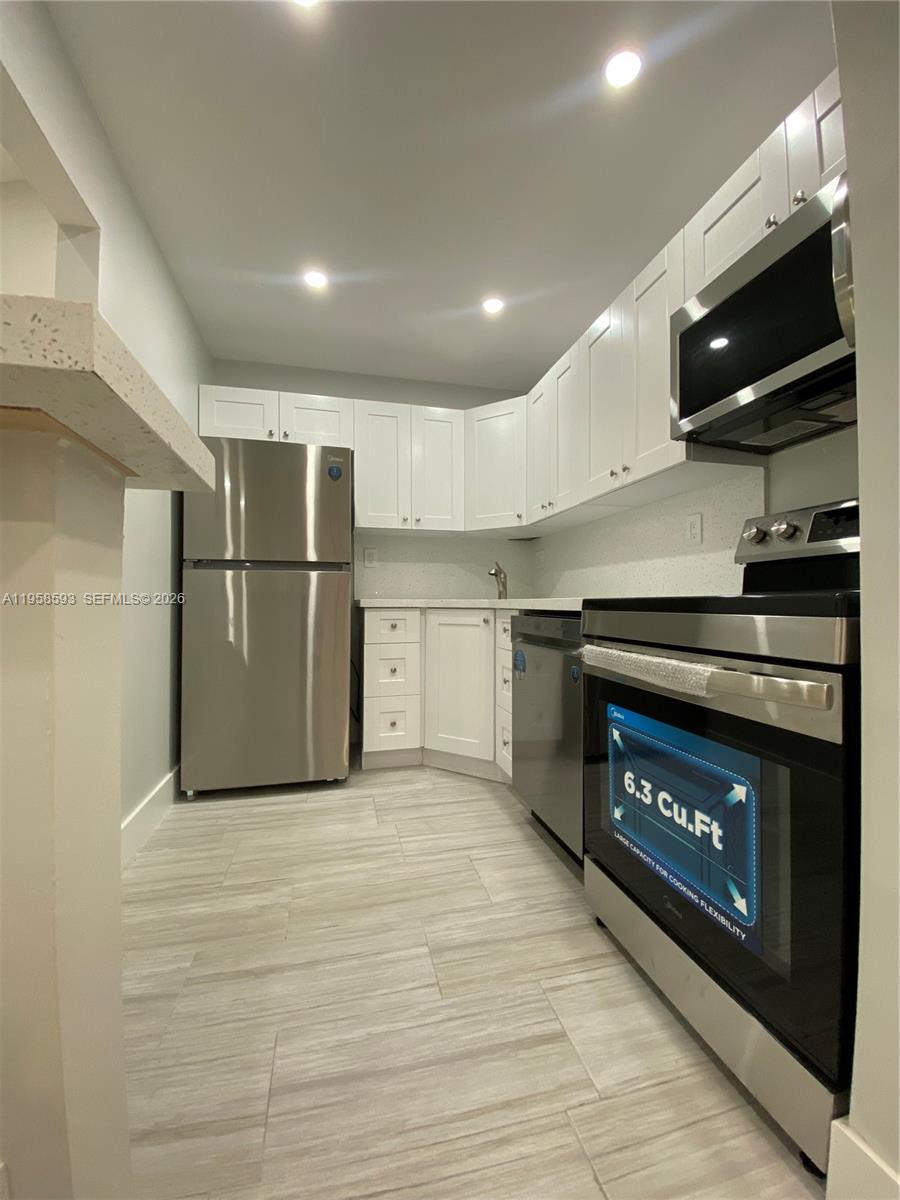 7175 Northwest 179th Street, Unit 302 Hialeah, FL 33015 - Photo 14 of 49 a kitchen with stainless steel appliances granite countertop a stove a refrigerator and a fireplace