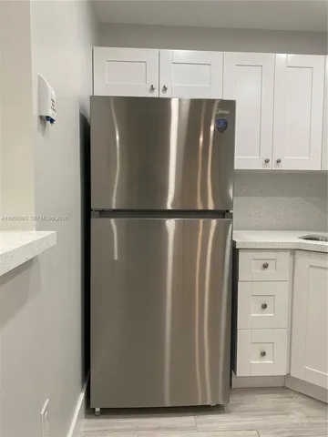 a view of a refrigerator in kitchen and white cabinets