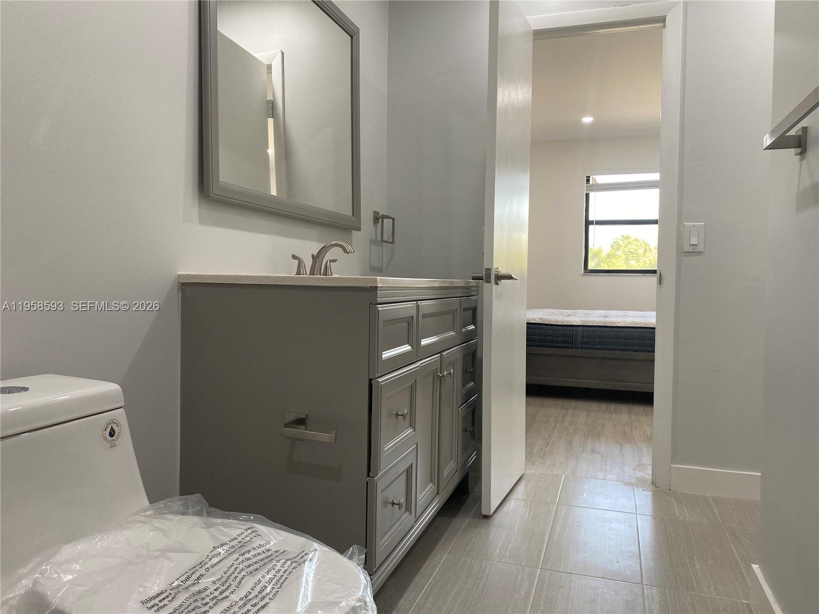7175 Northwest 179th Street, Unit 302 Hialeah, FL 33015 - Photo 22 of 49 a bathroom with a sink a toilet and mirror