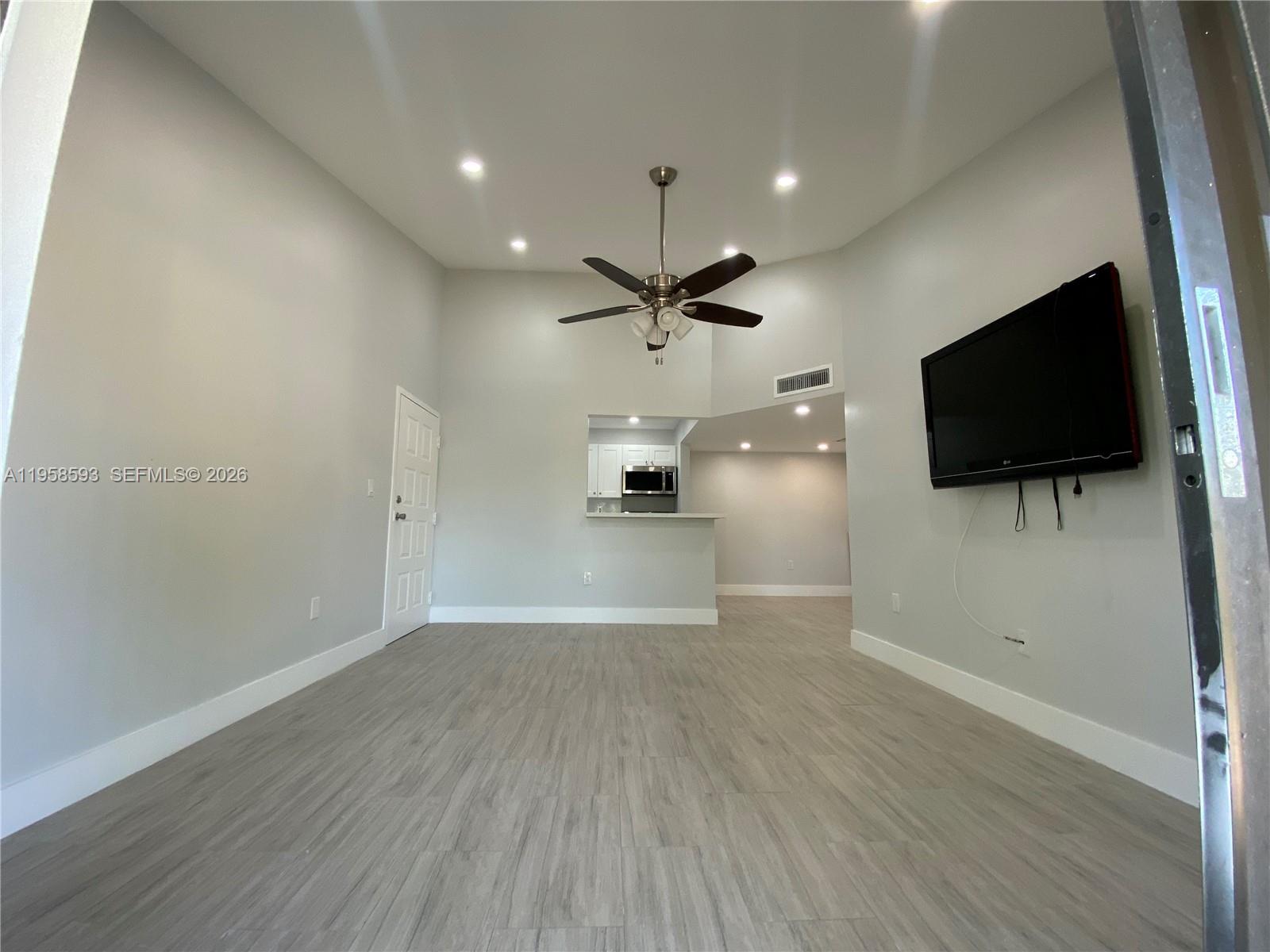 7175 Northwest 179th Street, Unit 302 Hialeah, FL 33015 - Photo 31 of 49 a view of a livingroom with a flat screen tv wooden floor and a ceiling fan