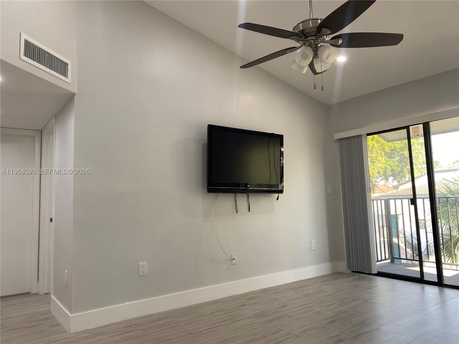 7175 Northwest 179th Street, Unit 302 Hialeah, FL 33015 - Photo 8 of 49 a living room with a flat screen tv and a large window