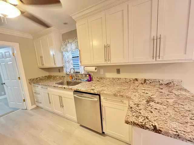 a kitchen with granite countertop white cabinets and white appliances