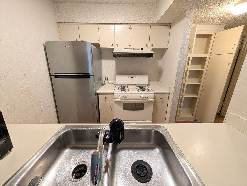 7801 Shoal Creek Boulevard, Unit 147 Austin, TX 78757 - Photo 4 of 15 a kitchen with a refrigerator a stove and a sink