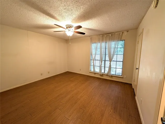 an empty room with wooden floor fan and windows