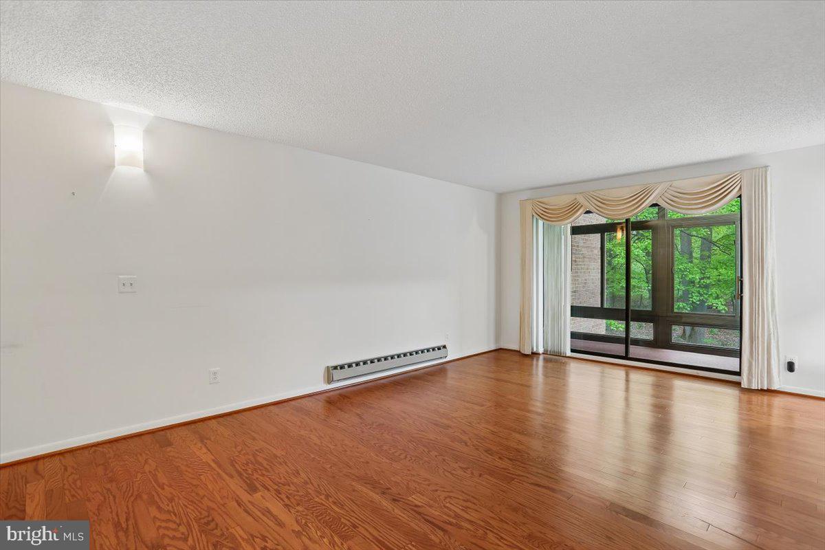 15210 Elkridge Way, Unit 912E Silver Spring, MD 20906 - Photo 9 of 48 a view of an empty room with wooden floor and a window
