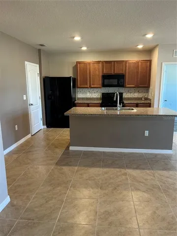 a view of kitchen with stainless steel appliances granite countertop a refrigerator and a stove top oven