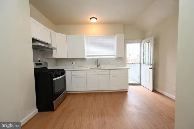 a white kitchen with wooden floor