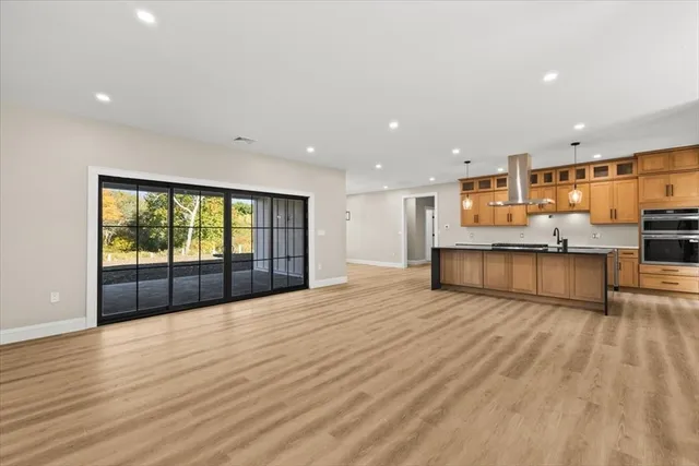 a view of an empty room with wooden floor and windows