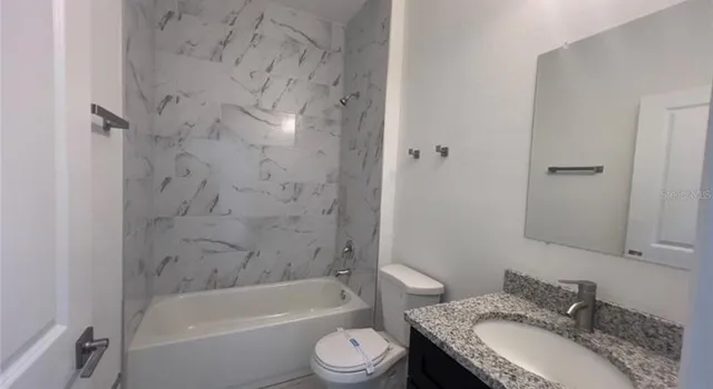 a bathroom with a granite countertop sink toilet a shower and a mirror