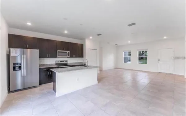 a kitchen with stainless steel appliances a sink a stove a microwave a refrigerator and cabinets