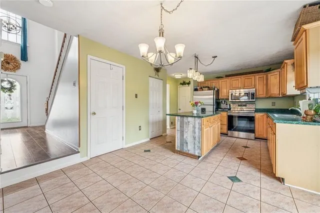 a kitchen with stainless steel appliances granite countertop a refrigerator a sink dishwasher a stove and white cabinets with wooden floor