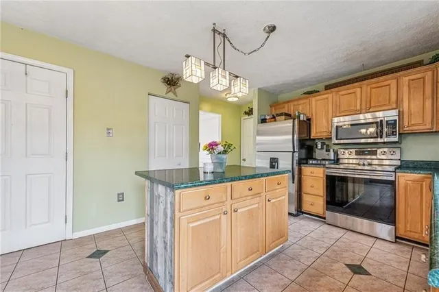 a kitchen with granite countertop a stove a sink and a refrigerator