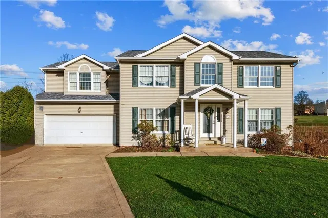 a front view of a house with a yard and trees