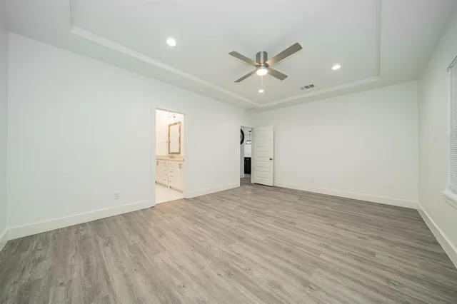 an empty room with wooden floor fan and windows