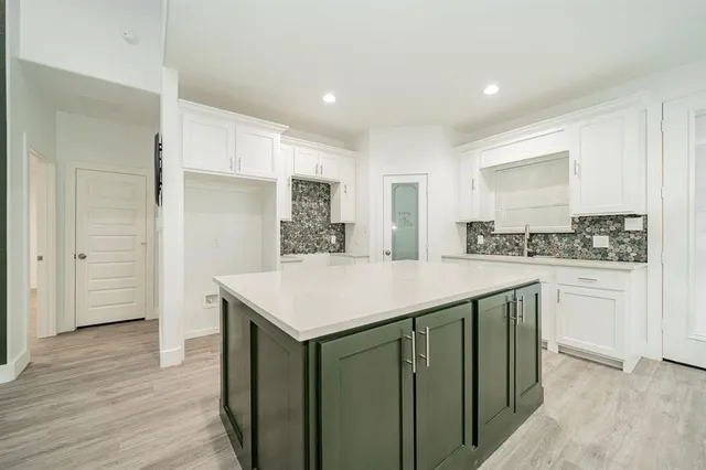 a kitchen with a sink a stove a refrigerator and white cabinets
