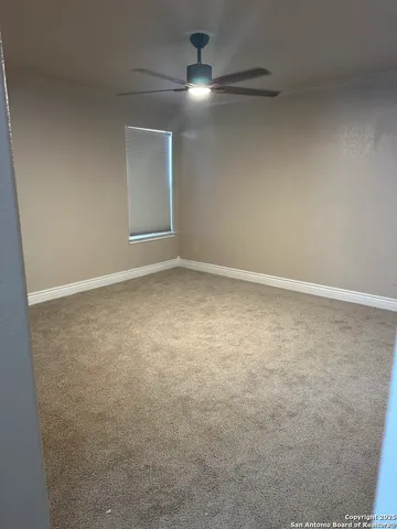 an empty room with ceiling fan and window