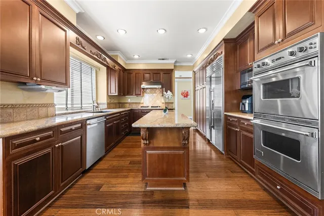 a kitchen with stainless steel appliances wooden floor sink stove and microwave