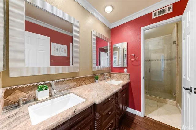 a bathroom with a granite countertop double vanity sink a mirror and shower