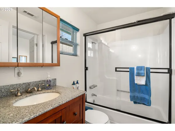 a bathroom with a granite countertop sink a mirror and shower