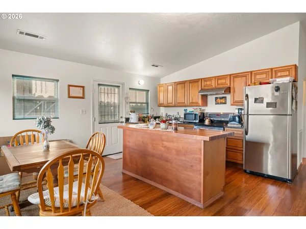 a kitchen with stainless steel appliances granite countertop a refrigerator a stove a sink dishwasher with a dining table and chairs