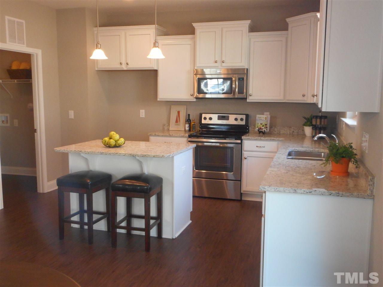 1509 Bentons Ridge Drive Raleigh, NC 27610 - Photo 14 of 23 a kitchen with stainless steel appliances a dining table chairs stove refrigerator and microwave