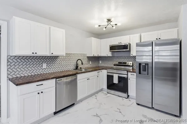 a kitchen with granite countertop a sink stainless steel appliances and white cabinets