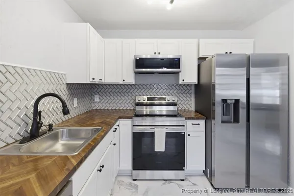 a kitchen with stainless steel appliances granite countertop a sink a stove a refrigerator and cabinets
