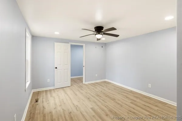 a view of room with a ceiling fan and wooden floor