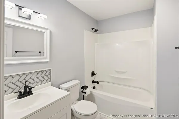 a view of a small house with a large tree and wooden fence