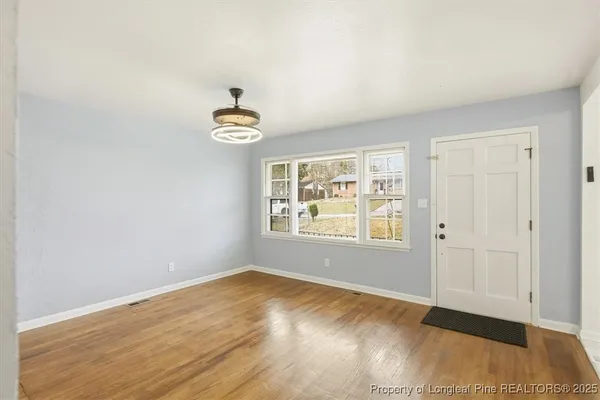 an empty room with wooden floor and windows