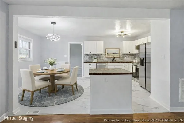 a kitchen with a dining table chairs and white cabinets