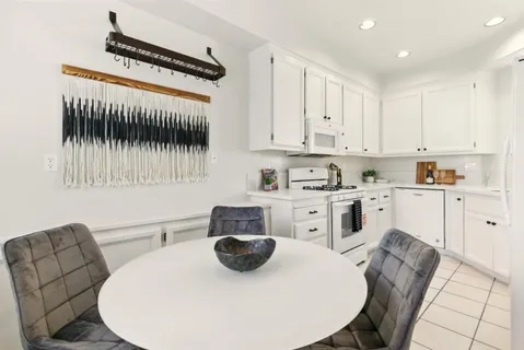 a kitchen with stainless steel appliances granite countertop a sink a stove a microwave a refrigerator and white cabinets