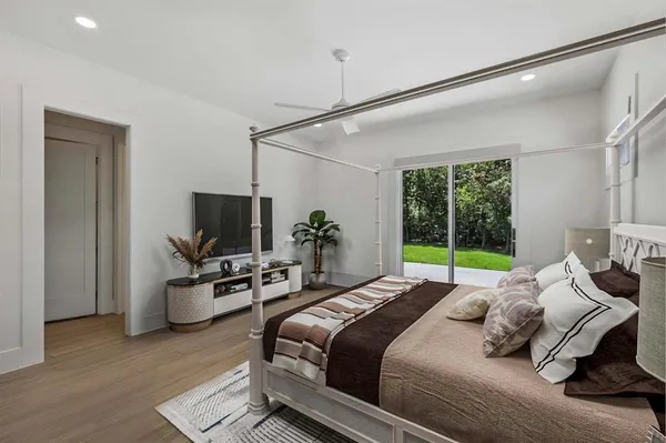 a bedroom with bed a flat tv screen and a potted plant