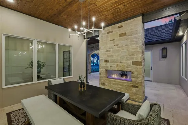 a living room with stainless steel appliances furniture a fireplace and a chandelier