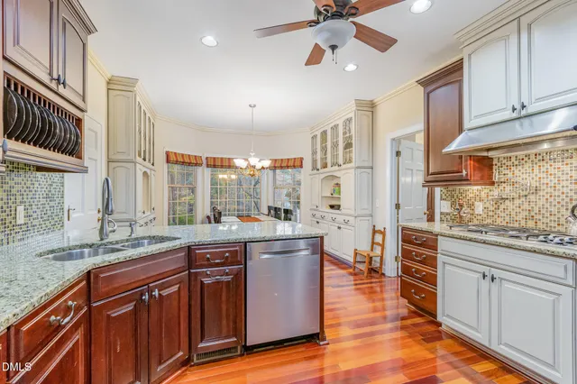 a large kitchen with stainless steel appliances granite countertop a refrigerator a sink dishwasher a stove and white cabinets with wooden floor