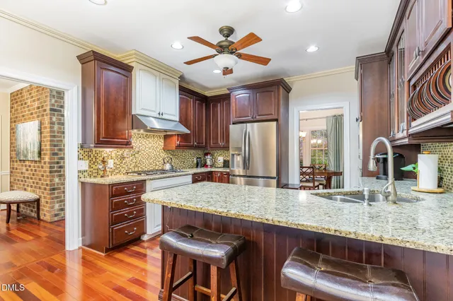 a kitchen with granite countertop a stove a sink a dining table and chairs