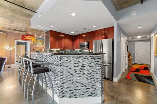 a kitchen with stainless steel appliances kitchen island granite countertop a refrigerator and a sink