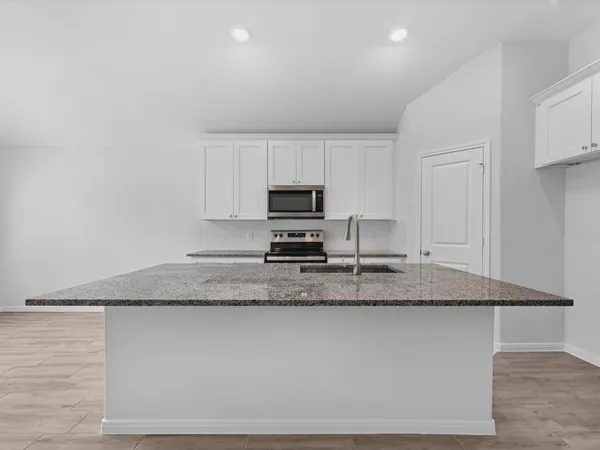 a kitchen with granite countertop a sink and a stove top oven