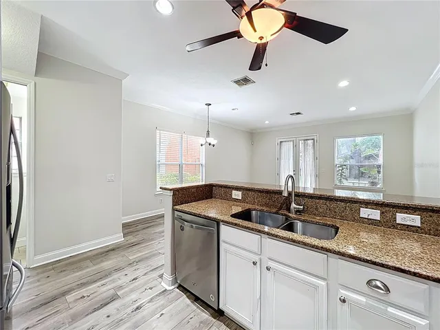 a kitchen with stainless steel appliances granite countertop a sink a counter space and a window