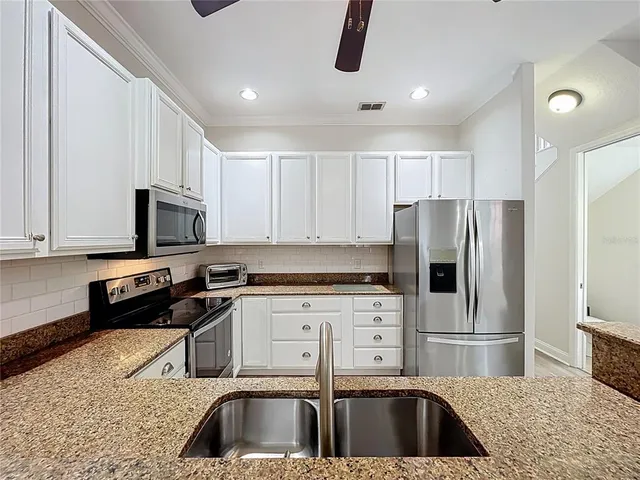 a kitchen with granite countertop a refrigerator stove and microwave