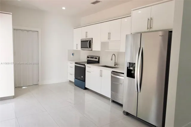a view of a refrigerator in kitchen and a sink