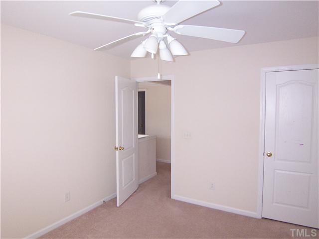 7605 Derek Drive Raleigh, NC 27613 - Photo 12 of 18 an empty room with a chandelier fan and windows
