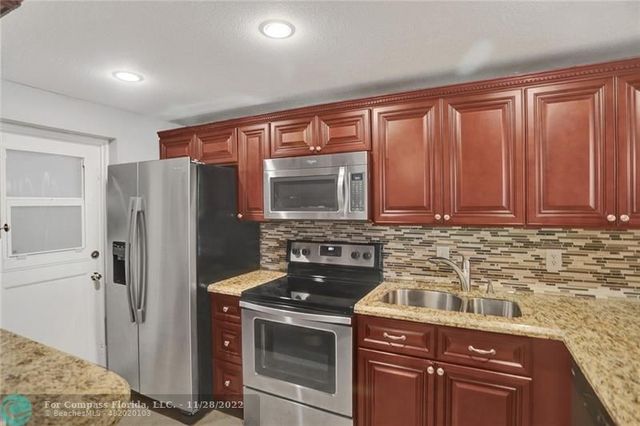 a kitchen with granite countertop a refrigerator stove and cabinets