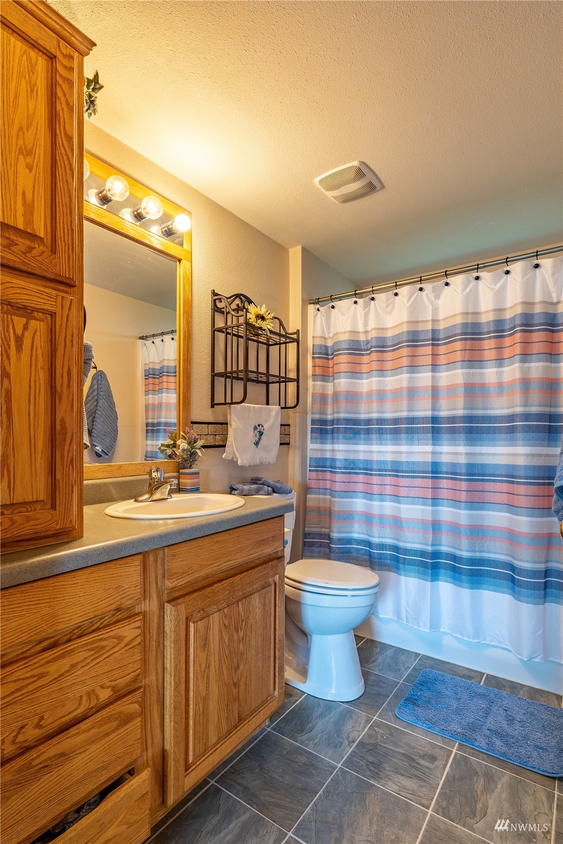 811 South Steele Road Othello, WA 99344 - Photo 26 of 40 a bathroom with a sink a toilet a mirror and shower curtain