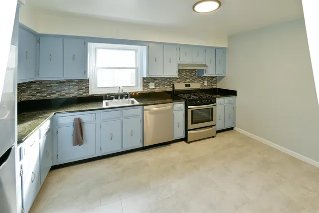 a kitchen with stainless steel appliances granite countertop a stove a sink and a microwave