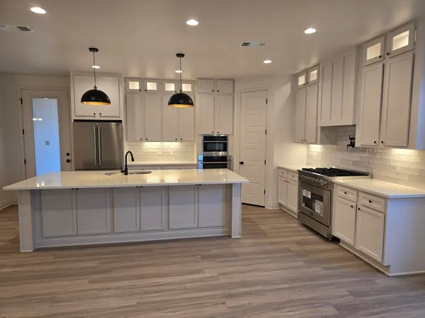 a large kitchen with stainless steel appliances granite countertop a stove a sink and a refrigerator