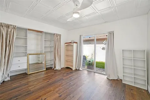 an empty room with wooden floor closet and windows