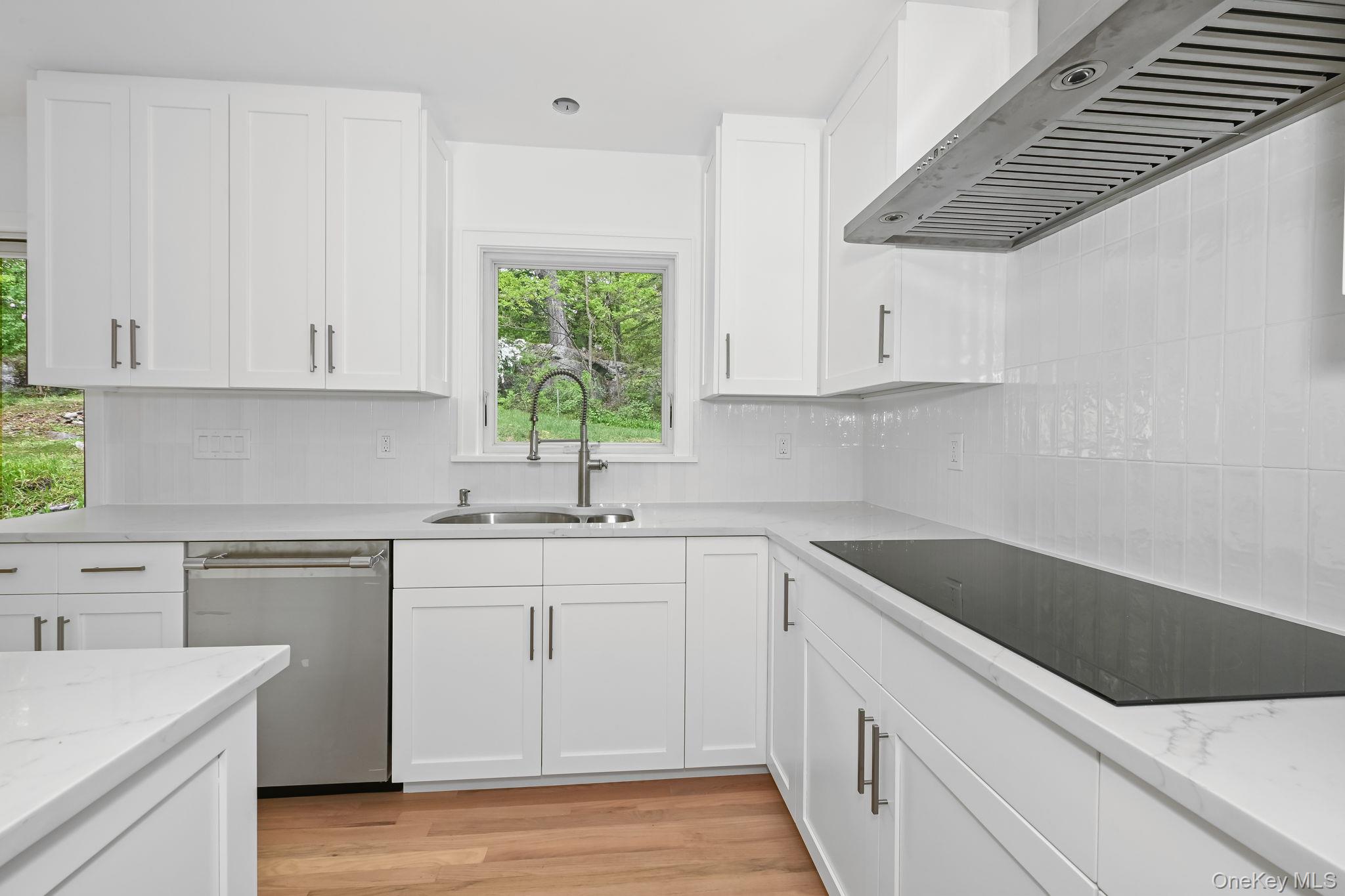 24 Country Road Mamaroneck, NY 10543 - Photo 6 of 37 a kitchen with a sink dishwasher a stove and white cabinets with wooden floor