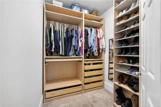 a view of walk in closet with clothes and shoes