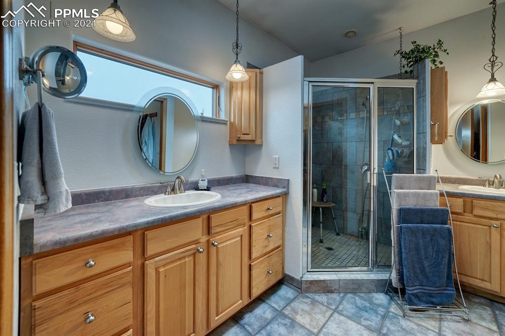 13770 Woodlake Road Elbert, CO 80106 - Photo 12 of 43 a bathroom with a granite countertop sink a mirror and shower